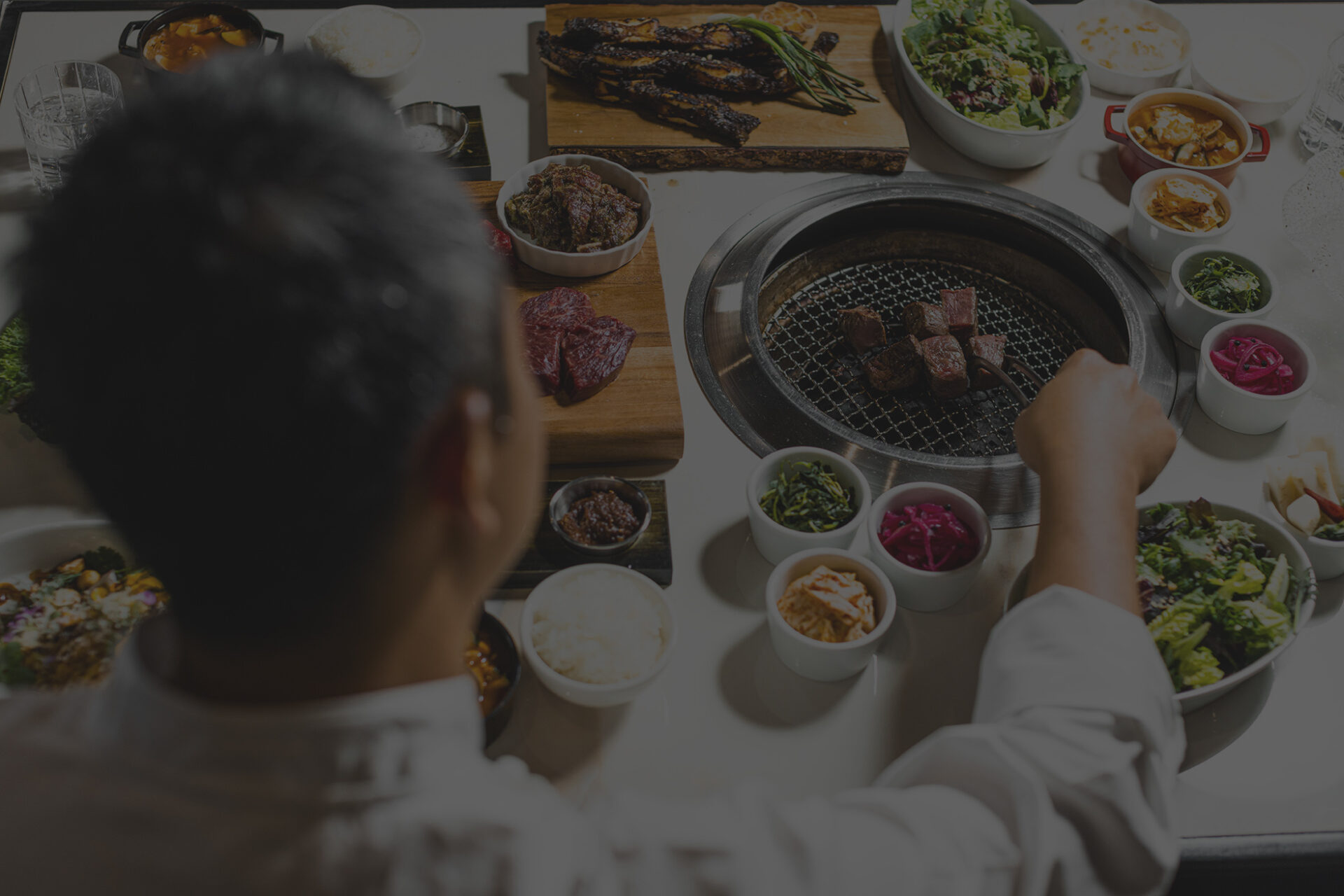 korean chef prepares steak on tableside grill